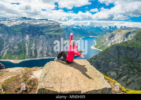Sportliche Frau posiert auf Trolltunga. Glückliche Wanderer genießen die schönen See und gutes Wetter in Norwegen. Stockfoto