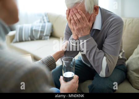 Erntegut mitfühlende Person Trostreiche älterer Mann in betreutes Wohnen Home holding Glas Wasser. Stockfoto