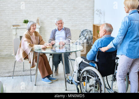 Krankenschwester in Zimmer mit älterer Mann im Rollstuhl ihn zu den Patienten des assisted living Home Einführung. Stockfoto