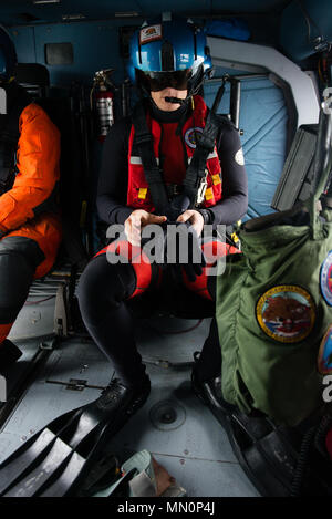 Coast Guard Petty Officer 2nd class Evan Staph, einer Luftfahrt überleben Techniker an der Coast Guard Air Station Cape Cod, bereitet seine Gang vor dem Sprung aus einem MH-60 Jayhawk Helikopter, während einer Suche und Rettung Übung mit Station Boston, Dienstag, August 8, 2017, im Hafen von Boston. Staph sprang in das Wasser aus dem schwebenden Hubschrauber und schwammen zum Bahnhof Boston's 45-Fuß-Boot retten. Us Coast Guard Foto von Petty Officer 3. Klasse Andrew Barresi Stockfoto