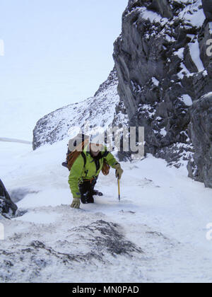 Männliche Bergsteiger Position auf einem steilen Schnee Gully und Couloir früh am Morgen auf dem Weg zu einer hochalpinen Gipfel in der Schweiz Stockfoto