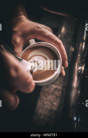 Barista gießt Milch, Cappuccino oder Latte Art getonten Bild Stockfoto