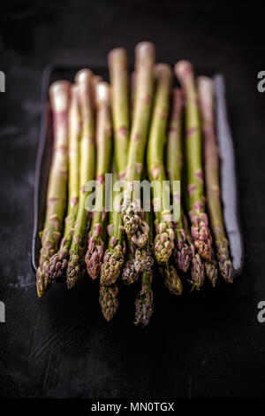 Frisches Grün nicht gegarten Spargel auf schwarzem Hintergrund Stockfoto