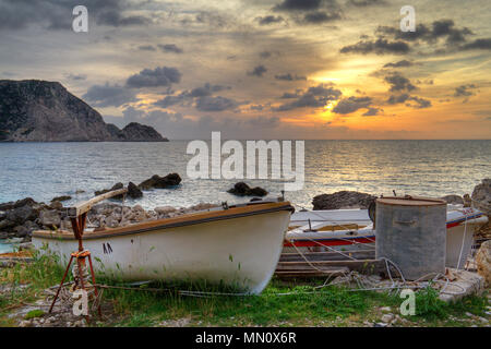 Sonnenuntergang über dem Ionischen Meer in der Nähe von Petani auf der griechischen Insel Kefalonia, im Vordergrund kleine Fischerboote aus dem Wasser gezogen Stockfoto