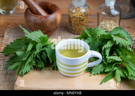 Eine Tasse Brennnesseltee mit frischen Blätter auf einem Tisch Stockfoto