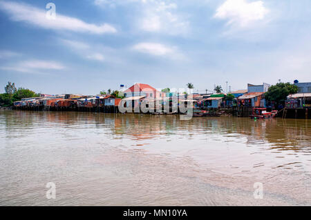 Holz- Häuser entlang dem Mekong River im Süden Vietnams an einem sonnigen Tag. Stockfoto