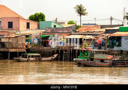 Holz- Häuser und Boote auf dem Mekong River im Süden Vietnams an einem sonnigen Tag. Stockfoto