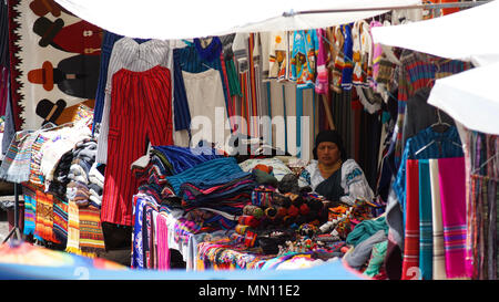 Indigene Frau sitzt und verkauft die Webereien und Kunsthandwerk in der Plaza de los Ponchos Stockfoto