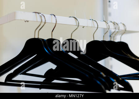 Leere Holz Kleiderbügel in leere Garderobe, Kleiderbügel Reihe alle schwarz. Leeren Kleiderschrank stand mit schwarz Kleiderbügel bei Business Veranstaltungsort. Stockfoto