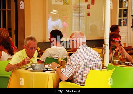 Touristen Mittagessen in einem Restaurant Bürgersteig entlang der R 25 de Abril Straße in der Altstadt, Lagos, Algarve, Portugal, Europa. Stockfoto