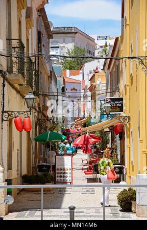 Touristen vorbei gehen Restaurants entlang der R Comendador Marinho in der Altstadt, Silves, Portugal, Europa. Stockfoto