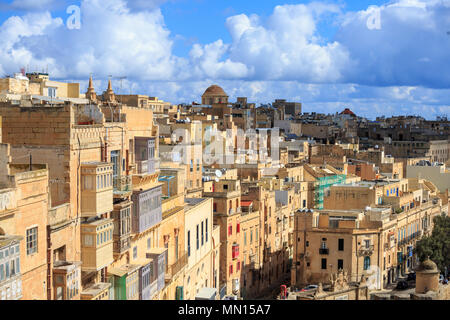 Malta, Valletta. Kapital mit hohen traditionellen Kalkstein Gebäude und überdachten Balkonen, unter einem blauen Himmel mit einigen Wolken. Stockfoto
