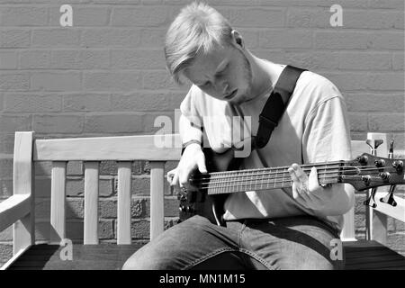 17-jährigen Teenager Kaukasier Männlich spielte Bass Gitarre im Freien. Stockfoto