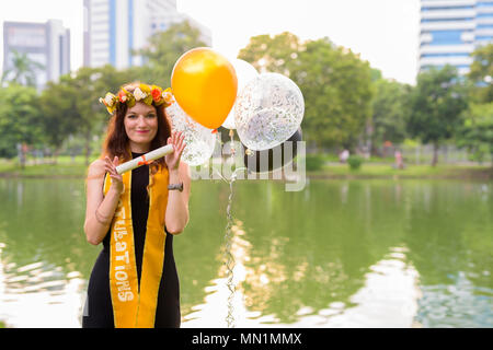 Junge schöne Frau Abschluss feiern im Park in Bang Stockfoto