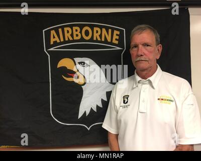 Dallas Braun, ein Vietnam Veteran, der Firma A, 2.BATAILLON, 327 Infanterie Regiment, 1. Brigade [eigene], Luftlandedivision stellt neben einem Screaming Eagle Flag, Aug 8, 2017 in Fort Campbell, Kentucky serviert. Braun, zusammen mit Tim Winterburg, Watson Baldwin, und Jay zu bewältigen, ist einer der Soldaten, die in den berühmten Vietnamkrieg Foto "Hilfe von Oben" von Kunst Greenspon. Als das Foto gemacht wurde, Braun war auf dem Boden Grimassen in den Schmerz von einer Verletzung während eines Feuergefechts mit der NVA getragen. (U.S Armee Foto von Sgt. William White) Stockfoto