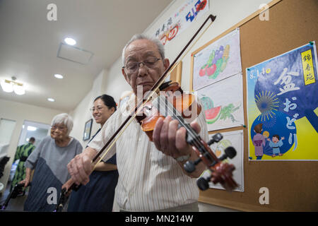 Yasuto Tahara, eine japanische Lokale und Pflegeheim Bewohner, spielt die Geige für amerikanische Besucher während des Festivals an Bon-Odori Kinjuen Pflegeheim in Iwakuni, Japan, August 14, 2017. Kulturelle Anpassung Gastgeber der Veranstaltung und lud Marine Corps Air Station Iwakuni Bewohner zu beteiligen und das Festival in der Krankenpflege zu Hause feiern. (U.S. Marine Corps Foto von Lance Cpl. Carlos Jimenez) Stockfoto