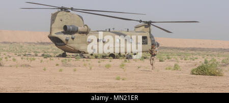 Ein Mitglied der irakischen Sicherheitskräfte bietet Sicherheit für eine CH-47 Chinook Hubschrauber vom 2-149 th Allgemeine Unterstützung Aviation Battalion, Task Force rauhen Mitfahrer während der Antenne Response Force Übung an Taji militärische Komplex, Irak, 13. August 2017. Die Schulung ist Teil des gesamten Combined Joint Task Force - inhärenten Building Partner Kapazität mission lösen, die über die Ausbildung und die Verbesserung der Fähigkeit der zusammengeschlossen, um Kräfte, die ISIS konzentriert. CJTF-OIR ist die globale Koalition zu besiegen ISIS im Irak und in Syrien. (US Army Foto vom Kapitän Stephen James) Stockfoto