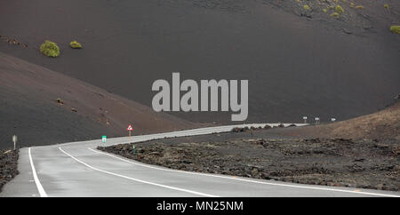 LANZAROTE, KANARISCHE INSELN, SPANIEN: Leere Asphaltstraße durch das trockene vulkanische Landschaft von Timanfaya Nationalpark führt. Stockfoto