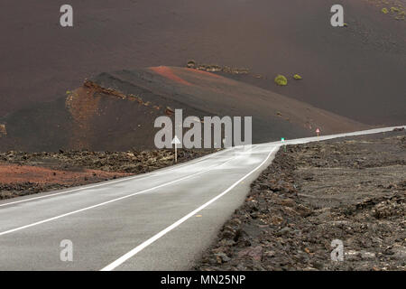 LANZAROTE, KANARISCHE INSELN, SPANIEN: Leere Asphaltstraße durch das trockene vulkanische Landschaft von Timanfaya Nationalpark führt. Stockfoto