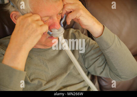 Ältere Mann legt auf eine Vorrichtung zur Schlafapnoe Stockfoto