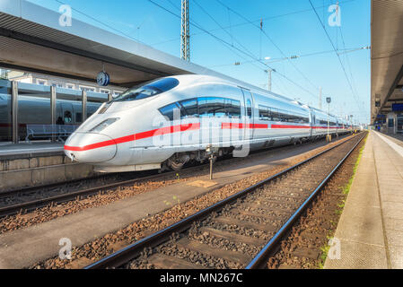 High speed weiße Zug auf dem Bahnhof bei Sonnenuntergang. Nürnberg, Deutschland. Moderne Intercity Zug auf den Bahnsteig. Industrial. Erstaunlich passe Stockfoto