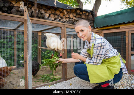 Junge Frau ihre freie Hühner füttern. Ei Legehennen und junge Frau Bauer. Gesunde organische Essen Lifestyle. Stockfoto