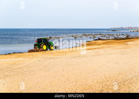 Corfu, Schweden - 30 April, 2018: Dokumentation des täglichen Lebens und. Grün John Deere 6120 Traktor Reinigung Algen und Steine vom Strand Stockfoto