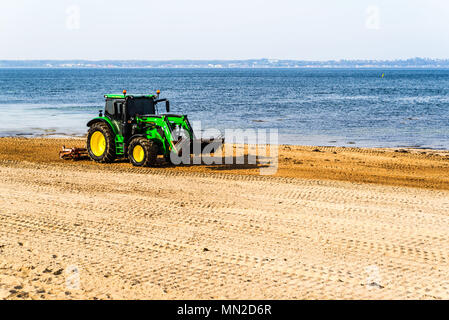 Corfu, Schweden - 30 April, 2018: Dokumentation des täglichen Lebens und. Grün John Deere 6120 Traktor Reinigung Algen und Steine vom Strand Stockfoto