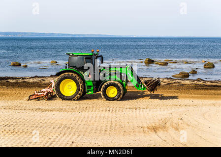 Corfu, Schweden - 30 April, 2018: Dokumentation des täglichen Lebens und. Grün John Deere 6120 Traktor Reinigung Algen und Steine vom Strand Stockfoto