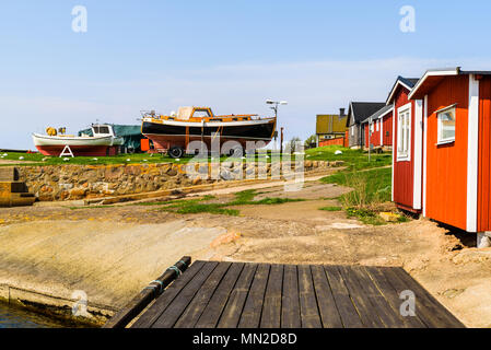 Nyhamnslage, Schweden - 30 April, 2018: Dokumentation des täglichen Lebens und. Red angeln Schuppen neben einem hölzernen Pier mit Vintage Boote auf dem Boden Stockfoto