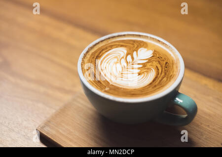 Close up heißen Cappuccino Tasse mit Herzform latte Kunst auf Holz Tisch im Cafe, Drak Tone Filter, Essen und Trinken Stockfoto