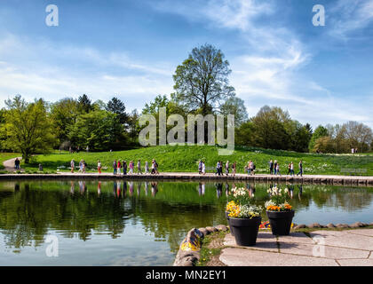 Britzer Garten, Neukölln, Berlin, Deutschland. 2018. Gartenblick, Topf plats outside Cafe am See und Menschen zu Fuß am See im Frühjahr Stockfoto