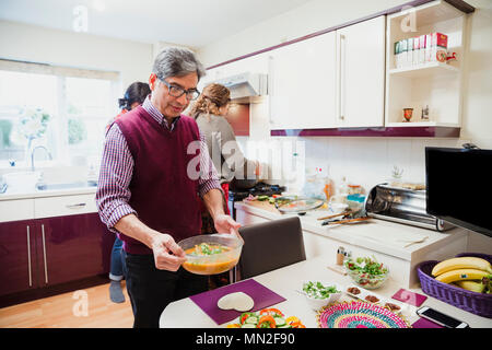 Reifer Mann ist die Verlegung der Tisch bereit für seine Familie zusammen essen zu teilen. Stockfoto
