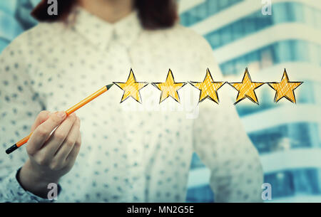 Junge Frau in der Nähe einen Bleistift in der Hand die Wahl von fünf Sterne Bewertung. Exzellenter Service Konzept. Stockfoto