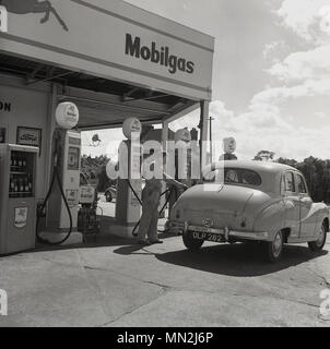 1950, historische, eine männliche Tankstelle attendant in Uniform füllen ein Auto mit Mobilgas Kraftstoff, England, UK. Stockfoto