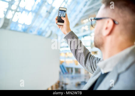 Zurück Porträt der Moderne junge Unternehmer unter Foto des Bürogebäudes, der Bildschirm des Smartphones konzentrieren, kopieren Raum Stockfoto