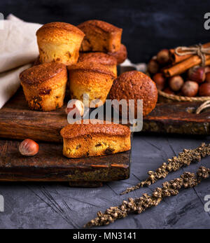 Gebackene Muffins mit trockenen Früchten und Trauben auf einem braunen Holzplatte, schwarz Tisch Stockfoto