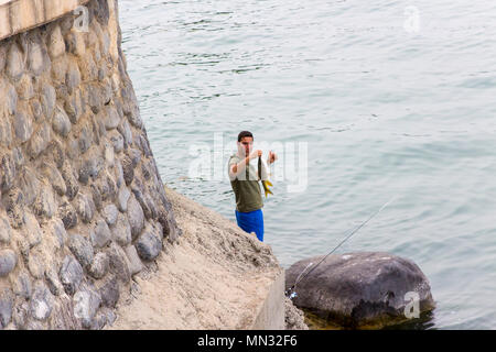 6. Mai 2018 Tiberias am See Genezareth Israel. Ein junger Mann angeln mit einem sich drehenden Stange und Spinner an einem diesigen Abends. Stockfoto