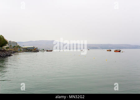 Die ruhigen glasklaren Wasser des See Genezareth mit angelegten Boote in den frühen Abend auf ein DUNSTIGER Tag im Mai 2018 Stockfoto