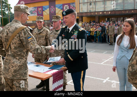 Oberst Charles Schnäpse, der stellvertretende Kommandeur der 45th Infantry Brigade Combat Team und Chief-of-Personal für die Gemeinsame Multinationale Ausbildung Gruppe - Ukraine, gratuliert einem graduierenden Cadet des Hetman Petro Sahaidachny nationale Armee Akademie in Lviv, Ukraine am 12.08.26. Die 45. IBCT ist in der Ukraine als Teil des Gemeinsamen multinationalen Ausbildung Gruppe - Ukraine Yavoriv Combat Training Center auf der internationalen Friedenssicherung und Security Center bereitgestellt. Die JMTG-U ist eine Koalition von Nationen zur Verbesserung der Ausbildung der Fähigkeit des CTC und Professionalität in der Uni gewidmet Stockfoto