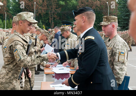 Oberst Charles Schnäpse, der stellvertretende Kommandeur der 45th Infantry Brigade Combat Team und Chief-of-Personal für die Gemeinsame Multinationale Ausbildung Gruppe - Ukraine, gratuliert einem graduierenden Cadet des Hetman Petro Sahaidachny nationale Armee Akademie in Lemberg, Ukraine, am 12.08.26. Der 45 IBCT ist in der Ukraine als Teil des Gemeinsamen multinationalen Ausbildung Gruppe - Ukraine Yavoriv Combat Training Center auf der internationalen Friedenssicherung und Security Center, westlich von Lemberg eingesetzt. Die JMTG-U ist eine Koalition von Nationen zur Verbesserung der Professionalität in der ukrainischen Armee gewidmet. (Phot Stockfoto