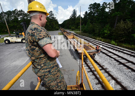 Die Joint Base Charleston Weapons Station ist eine US-amerikanische Militäreinrichtung in South Carolina, die den Transport von Marinemüstern und Logistikoperationen unterstützt. Am 21. August 2017 wartet ein Marine-Korporal, das dem Navy Munitions Command der Atlantic Unit Charleston Marine Corps Liaison Office zugewiesen ist, auf einen Zug, der während eines Containerdownloadvorgangs Munition transportiert. Das Archivfoto dokumentiert die dienststellenübergreifende Logistikkoordination mit der 628th Logistics Readiness Squadron. Stockfoto