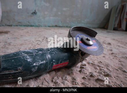 Seite Schleifer auf einem Boden vor einer dreckigen Mauer. Überholung Konzept Stockfoto