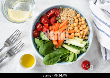 Blick von oben auf die Salatschüssel mit Quinoa, Kichererbsen, Gurken, Karotten, Spinat und Tomaten. Konzept der gesunden Ernährung, gesunde Lebensweise, Ernährung, Entgiftung Stockfoto