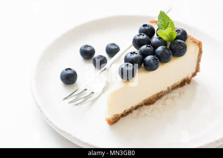 Stück Käsekuchen mit Heidelbeeren und minzeblatt auf Weiß. Detailansicht, selektive konzentrieren. New York Cheesecake Stockfoto