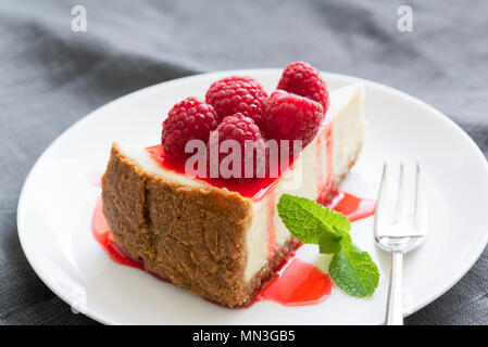 Käsekuchen mit Beeren Sauce und frische Himbeeren auf weiße Platte. Selektiver Fokus, horizontale Zusammensetzung Stockfoto