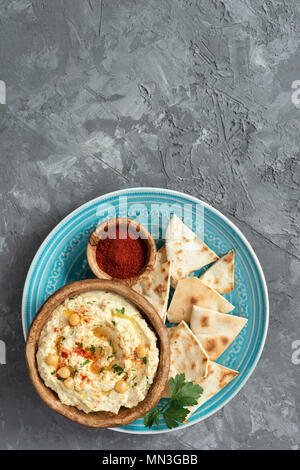 Kichererbse Hummus und Pita Chips auf konkreten Hintergrund. Ansicht von oben mit der Kopie Platz für Text. Arabisch, libanesisch, vegan und vegetarisch Dip oder Snack Stockfoto