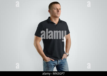 Vordere Mockup schwarz Polo Shirt auf einem Kerl ein Beispiel für Design. Der Mensch isoliert auf grauen Hintergrund. Stockfoto