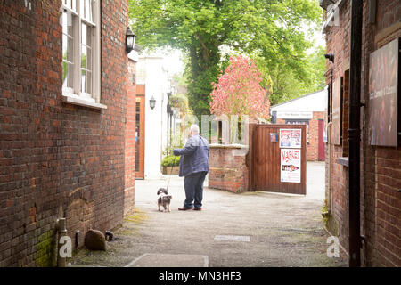 Man Walking bhis Hund an der Leine, dass erscheint in einer Gasse in Stevenage, Hertfordshire, England verloren zu haben Stockfoto