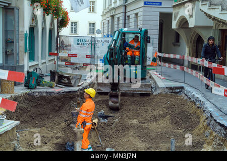 Luzern, Schweiz - Oktober 19, 2017: Arbeitnehmer in orange Uniformen Reparatur Kommunikation in der Altstadt und Baggern mit einem kleinen Bagger Stockfoto